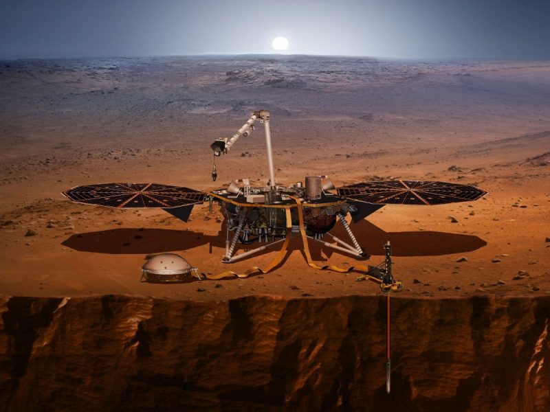 Wizja lądownika InSight na powierzchni Marsa. Po prawej widać Kreta wbitego w grunt. Po lewej, pod ochronną kopułą, przyrząd SEIS czyli sejsmograf. Rys. NASA/JPL-CALTECH